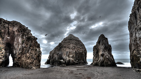 Felsen und schwarzer Sand an der chilenischen Küste bei Constitución